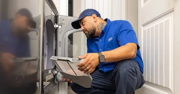 Technician handling a panel beside a residential dryer