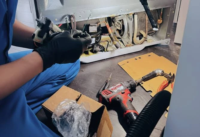Technician repairing the internal components of a microwave at a workbench