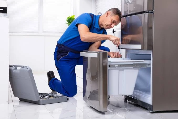 Technician inspecting the lower freezer drawer of a stainless steel refrigerator